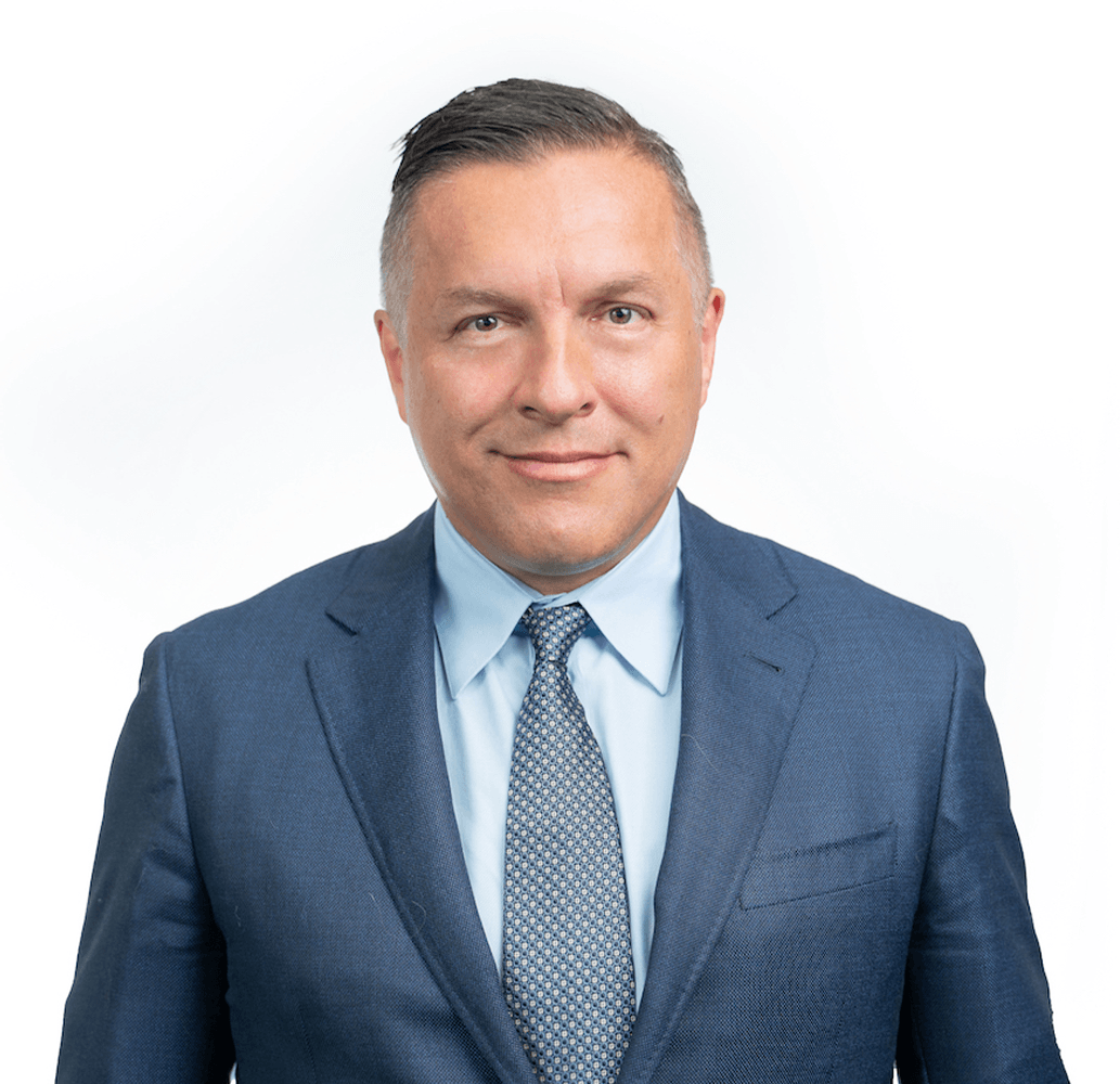 A man in a suit and tie is smiling for the camera